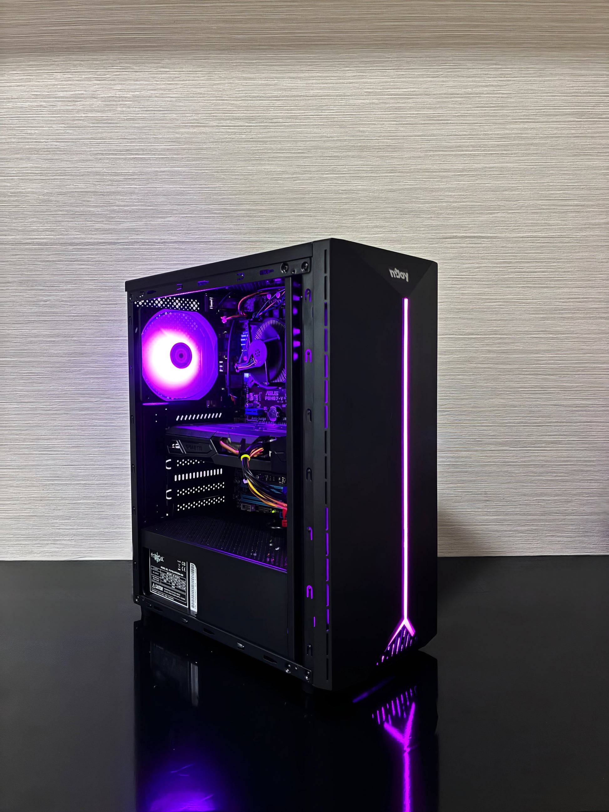 PC Gaming Bueno Start V3 prezentat din profil într-o carcasă nJoy Anil neagră, cu panou lateral din sticlă securizată prin care se observă componentele iluminate. Panoul frontal de tip mesh lasă să se vadă ventilatorul Antec, iar în partea din spate se remarcă ventilatorul cu inel RGB aprins în culori vibrante, creând un efect vizual modern.