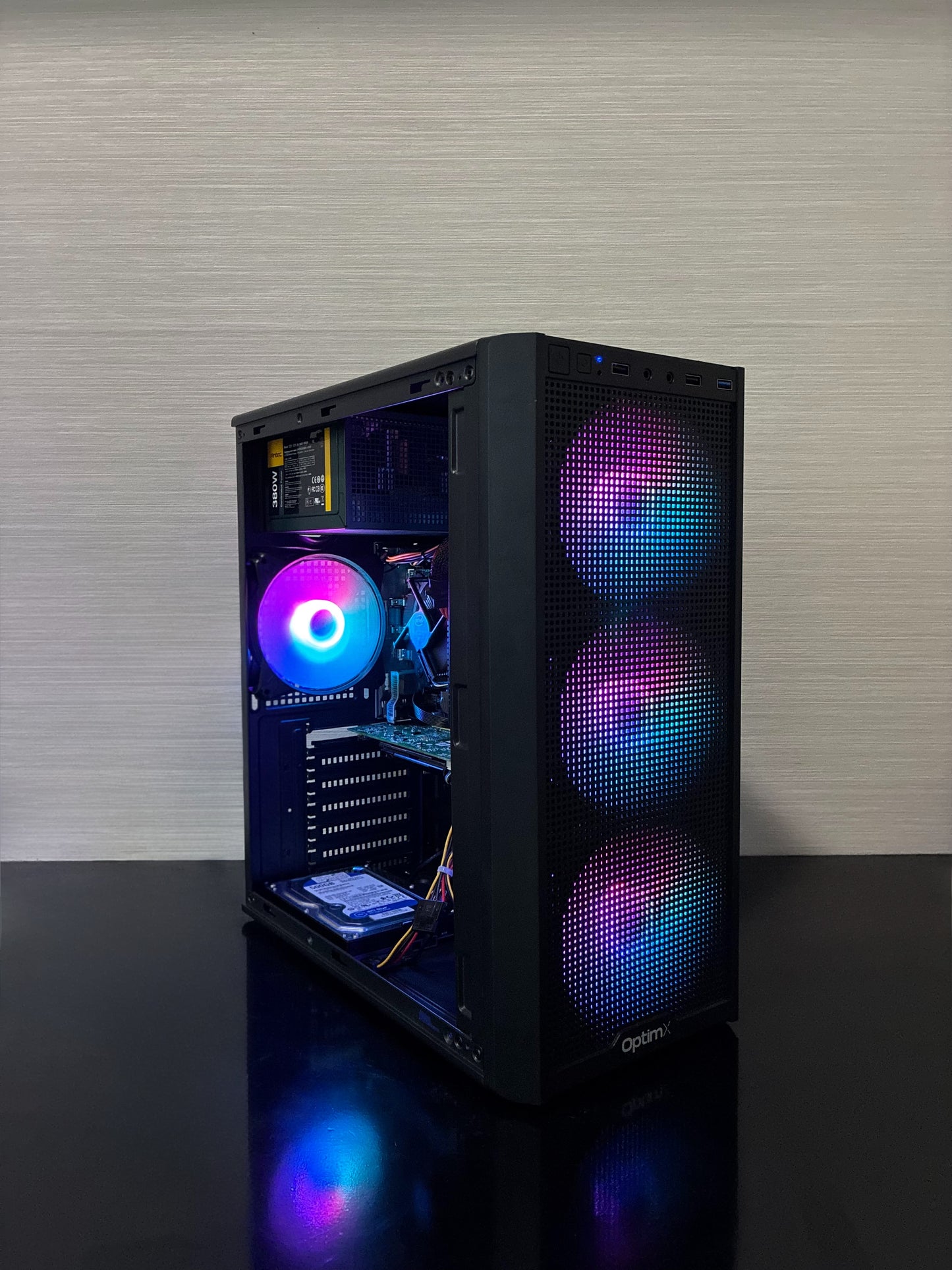 Carcasa de gaming a PC-ului BUENO SUMMER V3 iluminată în timpul funcționării, așezată pe un birou modern, evidențiind designul compact și panoul lateral