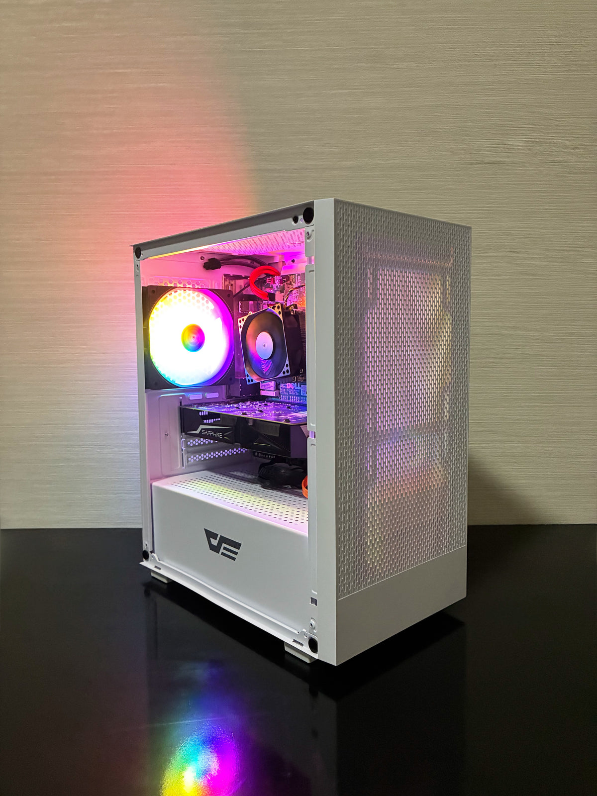 PC Gaming Bueno Run V2 asamblat într-o carcasă elegantă DarkFlash Mesh White, cu panou frontal perforat pentru un flux de aer optim și panou lateral din sticlă securizată. În partea din spate se remarcă ventilatorul DarkFlash cu iluminare RGB, adăugând un accent vizual modern pe fondul alb al carcasei.
