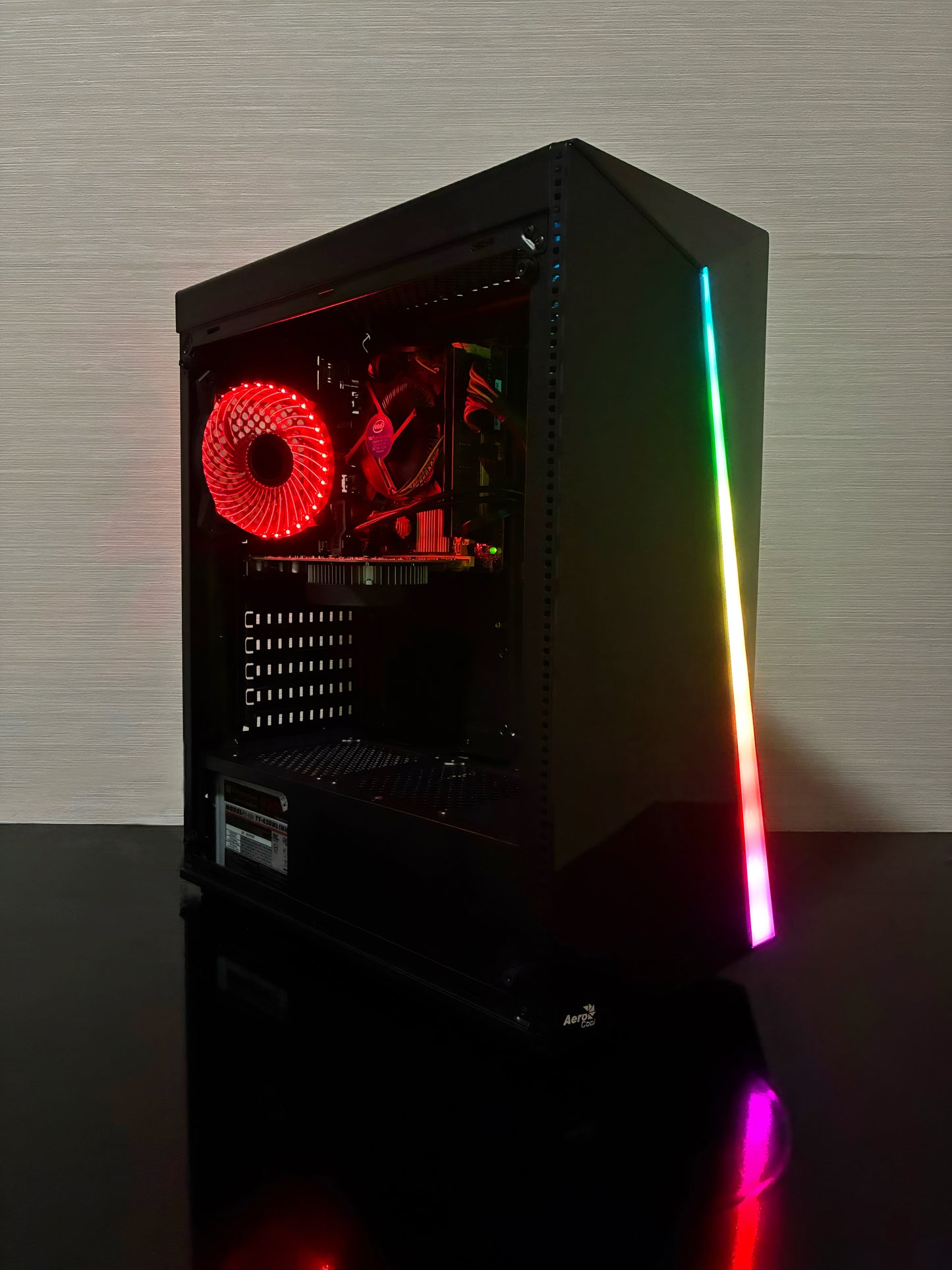 Un sistem PC Gaming BUENO START V2, asamblat într-o carcasă neagră Aerocool RGB. Imaginea prezintă panoul lateral transparent, prin care se văd componentele: procesorul Intel Xeon, placa video NVIDIA GTX 1050 2GB, cei 16GB RAM și stocarea duală (SSD de 256GB și HDD de 500GB). Se observă iluminarea RGB de la ventilatorul Antec din față și ventilatorul spate cu LED Genesis.