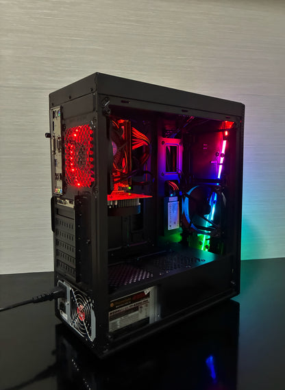 Carcasa neagră Aerocool RGB a PC-ului Gaming BUENO START V2, văzută din față-lateral. Panoul frontal mesh și panoul lateral transparent evidențiază efectele de iluminare ale ventilatorului Antec RGB și ale ventilatorului spate LED Genesis. Carcasa are un design modern, compact, perfect pentru o configurație de gaming de buget.